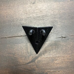 May include: Black triangular wall mount with two small holes on the top edge.