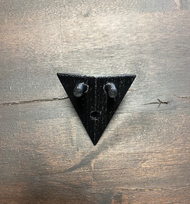 May include: Black triangular wall mount with two small holes on the top edge.