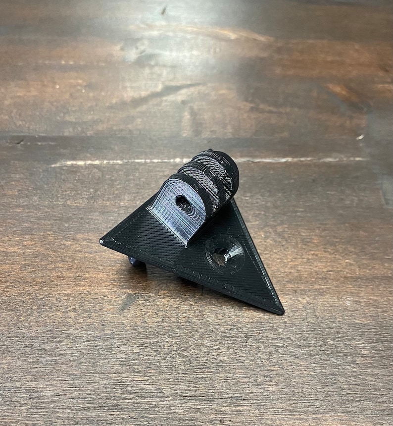 May include: A black 3D printed triangular camera mount with a GoPro-style mount on top.