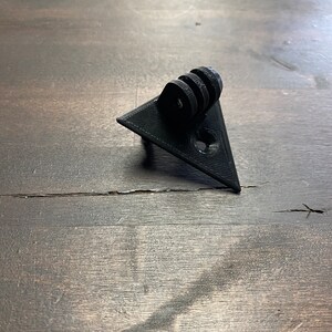 May include: Black plastic triangular camera mount with a GoPro-style mount on top.