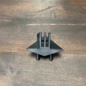 May include: Black plastic 3D printed GoPro mount with a triangular base and four legs.