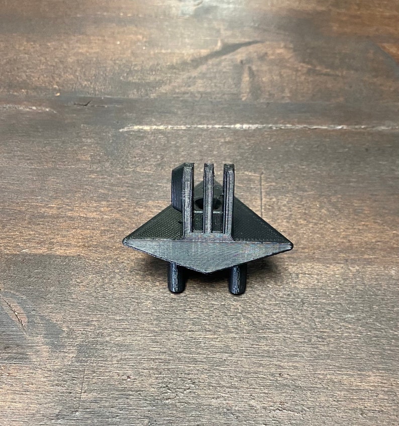 May include: Black plastic 3D printed GoPro mount with a triangular base and four legs.