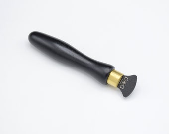 Może przedstawiać: Narzędzie z czarnym drewnianym uchwytem, złotą metalową obręczą i czarnym ostrzem o zaokrąglonym końcu. Ostrze jest oznaczone "G&G Tools".