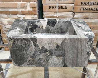 May include: A black and grey stone rectangular sink with a square basin. The sink is sitting on a metal frame.