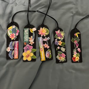 May include: Five black bookmarks with floral designs and black cords. Each bookmark features colorful flower and bird illustrations. Text on the bookmarks includes "Floral Fantasy", "Paradise", and "Blooms & Blossoms".