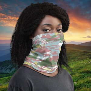 Puede incluir: Una persona lleva una cubierta facial con un patrón de camuflaje en tonos de rosa, verde, azul y amarillo. El patrón es abstracto y se asemeja a pinceladas.
