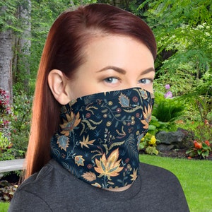 Puede incluir: Una mujer usando una máscara facial de patrón negro y azul con diseños florales. La máscara está hecha de una tela suave y transpirable y está diseñada para ser cómoda de llevar.