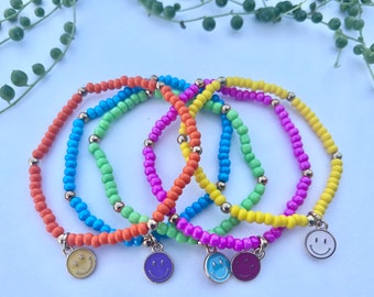 May include: Five colorful beaded bracelets with smiley face charms. The bracelets are orange, blue, green, pink, and yellow.