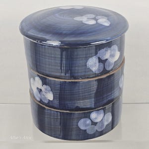 Set di piattini impilabili a più livelli in gres Jubako, Giappone, con coperchio a fantasia floreale blu e bianca.