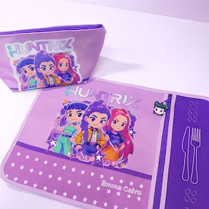 Può includere: Un set viola composto da un beauty case e un sottopiatto con la scritta "HUNTRIX" e illustrazioni di cartoni animati di quattro ragazze. Il sottopiatto ha un motivo a stelle, il nome "Emma Calvo" e una grafica di posate.