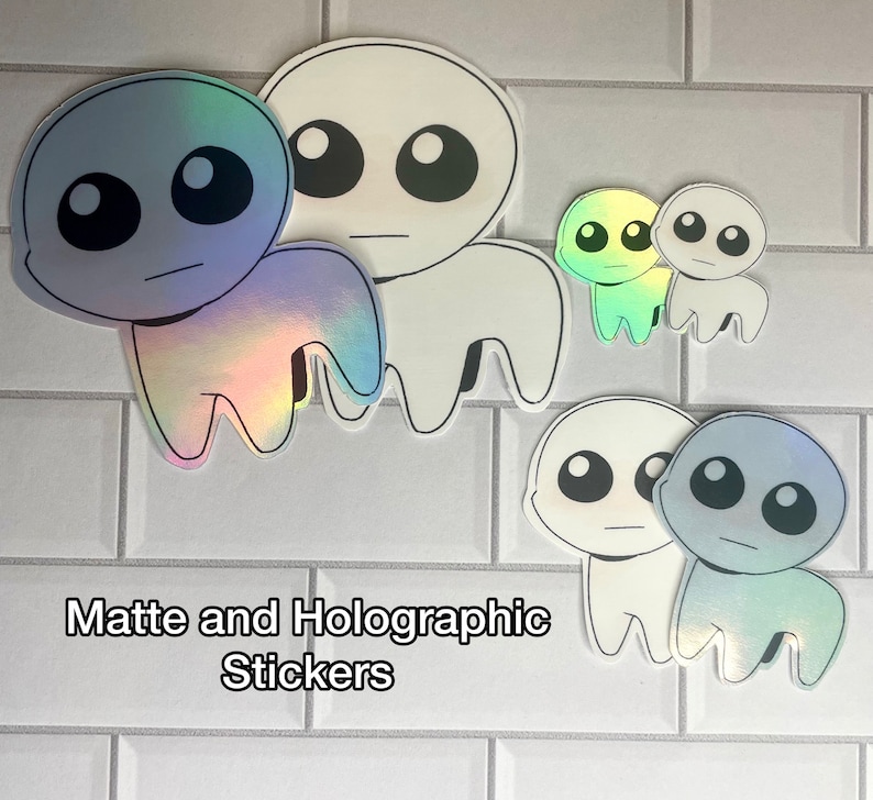 May include: A set of four holographic and matte stickers featuring a cartoon character with large eyes and a simple design. The stickers are in various sizes and colors, including blue, green, and white.