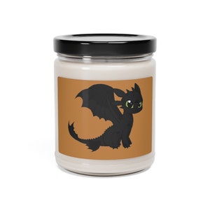 Peut inclure: Un bocal en verre pour bougie avec un couvercle noir et une étiquette blanche. L'étiquette représente un dessin animé d'un dragon noir aux yeux verts sur un fond brun.