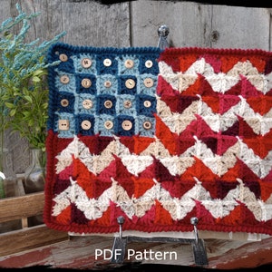 May include: Crochet pattern for an American flag with red, white, and blue yarn. The flag is made with a chevron pattern and has buttons sewn on the blue field. The pattern is called "Country Life in Crochet" and is available as a PDF download.