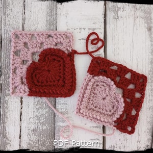Puede incluir: Dos cuadrados de crochet con corazones. Un cuadrado es rosa con un corazón rojo, y el otro es rojo con un corazón rosa. Los cuadrados están sobre un fondo de madera blanca. Patrón PDF.