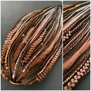 Puede incluir: Primer plano de rastas marrones, melocotón y blancas. Las rastas están adornadas con cuentas, plumas y detalles florales. El estilo presenta una mezcla de texturas y colores, creando un aspecto único y artístico.