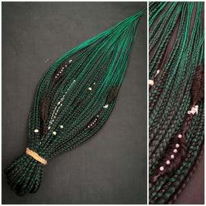 May include: A bundle of green and black braided hair extensions. The braids are decorated with black accents and small white beads. The hair is tied together with a tan string.
