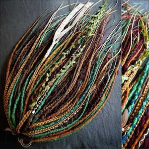Könnte beinhalten: Handgefertigte Dreadlocks in verschiedenen Braun-, Grün- und Goldtönen, mit Akzenten in Blau und Weiß. Einige sind geflochten, andere mit künstlichem Grün und weißer Spitze verziert. Ein böhmisches Haaraccessoire.