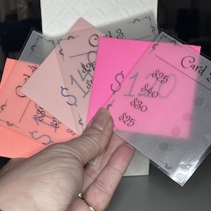 May include: Four pink and orange cards with black text and decorative borders. The cards are labeled "Card 1", "Card 2", "Card 3", and "Card 4". The cards have different dollar amounts written on them.
