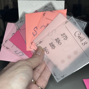 May include: A stack of pink and peach paper cards with black text and dollar signs. The top card is labeled "Card 8" and has the prices $60, $85, $30, and $75.
