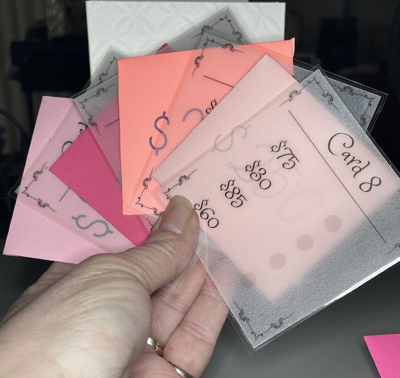 May include: A stack of pink and peach paper cards with black text and dollar signs. The top card is labeled "Card 8" and has the prices $60, $85, $30, and $75.