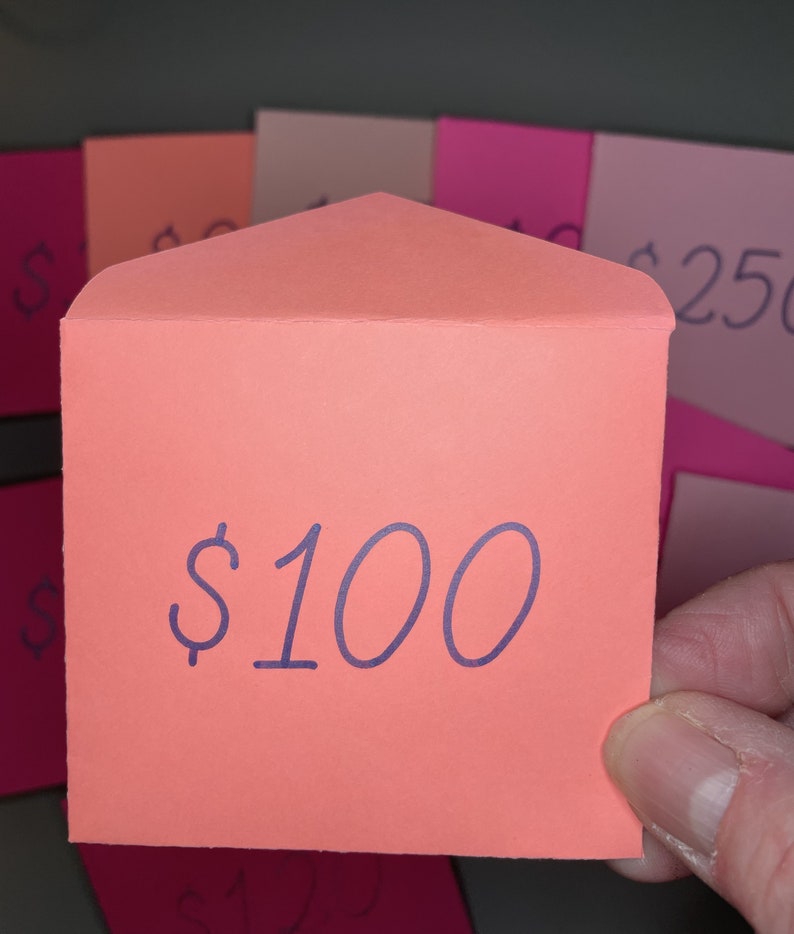 May include: A bright orange envelope with a folded flap. The envelope has the text "$100" written in purple ink.