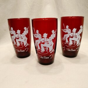 Puede incluir: Tres vasos de vidrio rojo con siluetas blancas de una banda tocando música. Cada vaso tiene las palabras "Hoe Down" impresas en la parte inferior.