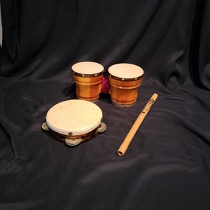 Könnte beinhalten: Ein Set aus drei Holz-Schlaginstrumenten: zwei braune Bongos mit weißen Fellen und ein braunes Tamburin mit silbernen Schellen. Ein Holzstab ist im Lieferumfang enthalten.