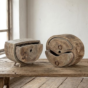 May include: Two rustic wooden storage boxes. One is a half-circle shape with a drawer, and the other is a yin-yang shape with two drawers. Both are made from weathered wood and sit on a wooden table.
