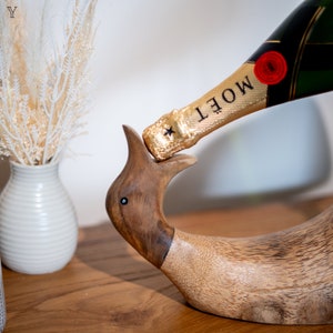 Pu&ograve; includere: Un porta bottiglie in legno a forma di uccello con una bottiglia dorata di champagne Mo&euml;t che riposa nel suo becco.
