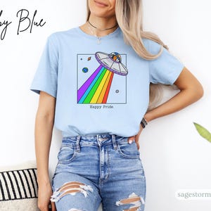 Pu&ograve; includere: T-shirt azzurra con una grafica di un UFO che emette un arcobaleno. La maglietta ha le parole "Happy Pride" e "Baby Blue" stampate sopra. La maglietta &egrave; realizzata in un materiale morbido ed &egrave; adatta per l'abbigliamento casual.