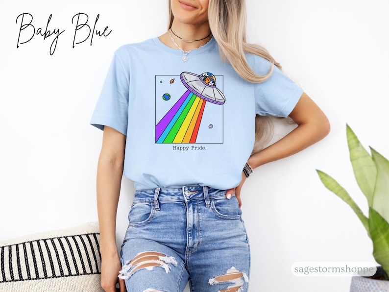 Pu&ograve; includere: T-shirt azzurra con una grafica di un UFO che emette un arcobaleno. La maglietta ha le parole "Happy Pride" e "Baby Blue" stampate sopra. La maglietta &egrave; realizzata in un materiale morbido ed &egrave; adatta per l'abbigliamento casual.
