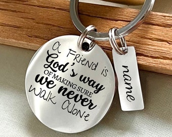 May include: A silver keychain with a round charm that says "A friend is God's way of making sure we never walk alone". There is a smaller tag attached to the keychain that says "name".