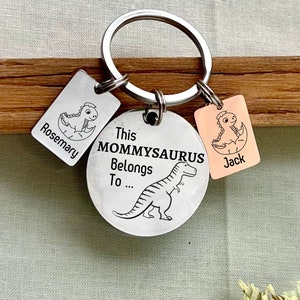 May include: A silver keychain with a round tag that says "This Mommysaurus Belongs To..." and a dinosaur illustration. There are two smaller tags attached to the keychain, one says "Rosemary" and the other says "Jack".