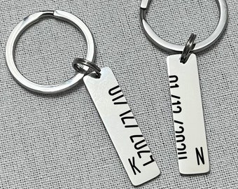 May include: Two silver keyrings with engraved tags. The tag on the left says "I love you" with the letter "K" at the bottom. The tag on the right says "11/03/19" with the letter "N" at the bottom.