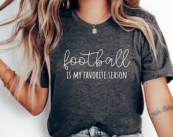 May include: A dark gray t-shirt with the text "football is my favorite season" in white script font.
