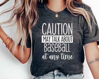 May include: A dark grey t-shirt with white text that reads "CAUTION MAY TALK ABOUT BASEBALL at any time".
