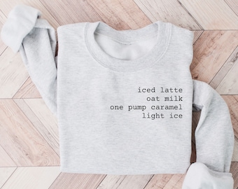 May include: Gray sweatshirt with the text "iced latte oat milk one pump caramel light ice" printed on the front.