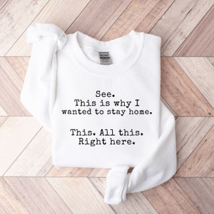 May include: White sweatshirt with the text "See. This is why I wanted to stay home. This. All this. Right here." printed in black.