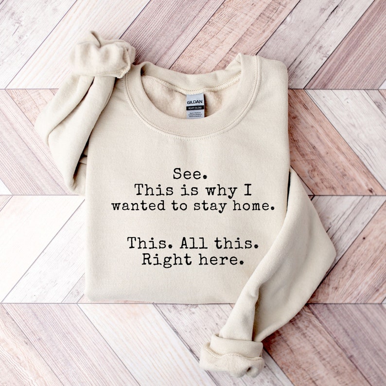 May include: A beige sweatshirt with the text "See. This is why I wanted to stay home. This. All this. Right here." printed in black.