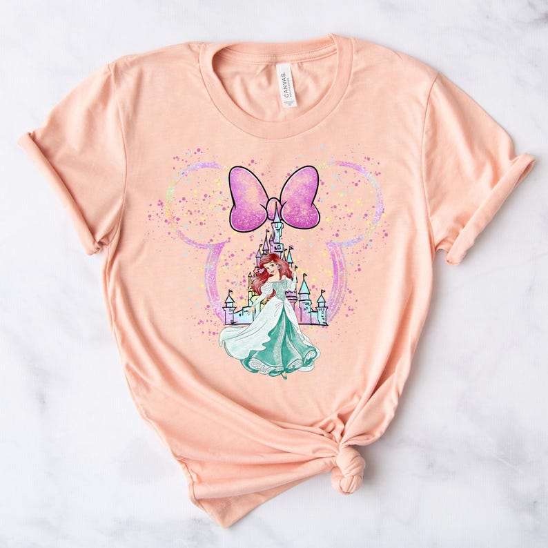 Puede incluir: Camiseta de color melocot&oacute;n con un lazo rosa, un castillo y una princesa con un vestido verde. El dise&ntilde;o est&aacute; rodeado de purpurina.