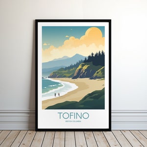 Op de afbeelding: Een ingelijste kunstprint met een kustlandschap met strand, zee en bergen onder een zonnige hemel. De print bevat het woord "TOFINO" en "BRITISH COLUMBIA" in een turquoise lettertype.