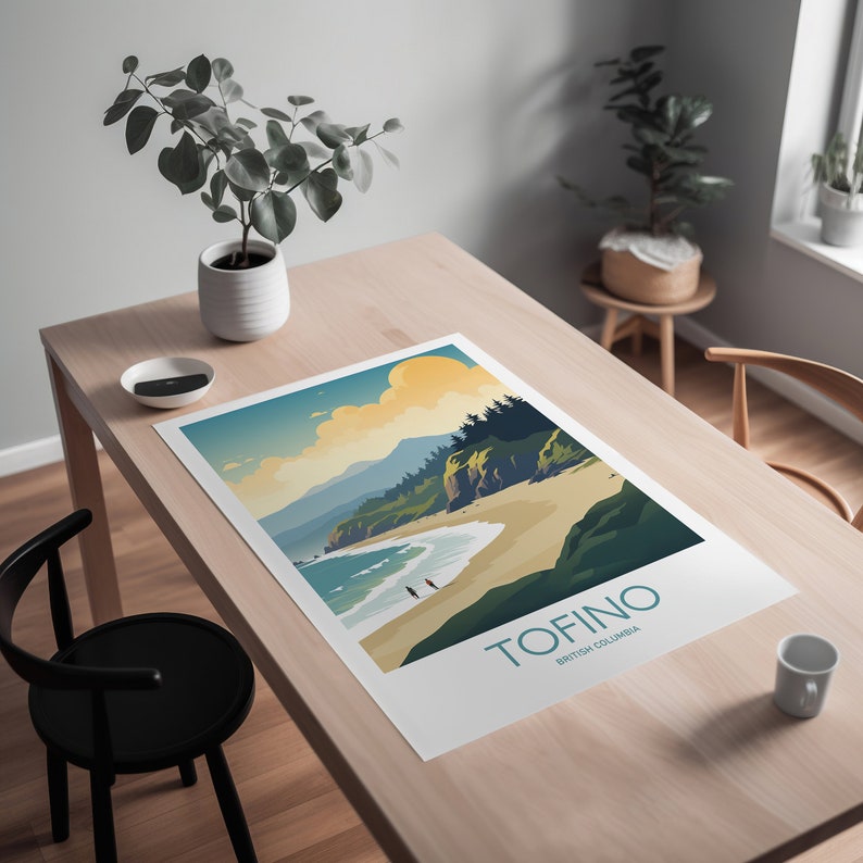 Op de afbeelding: Een ingelijste kunstafdruk van Tofino, British Columbia, met een kustlandschap met een strand, oceaan en bergen. De print heeft een minimalistische stijl met turquoise, beige en groene tinten. Het woord "Tofino" is in turquoise gedrukt.