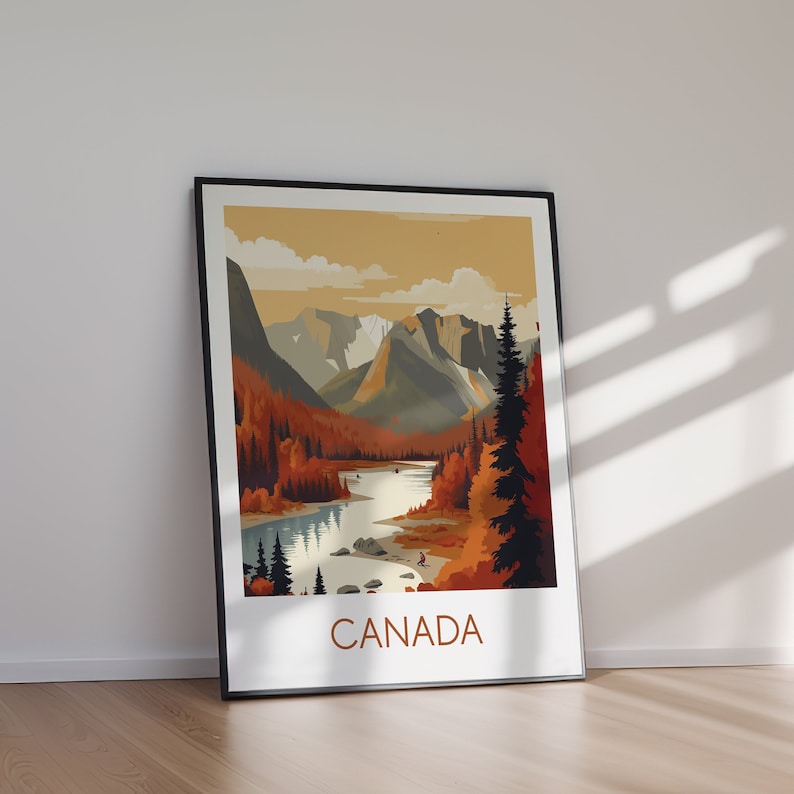 May include: A framed art print featuring a scenic landscape of Canada. The artwork depicts a river winding through a valley, surrounded by mountains and autumn-colored trees. The word "CANADA" is printed in a bold font at the bottom of the print.