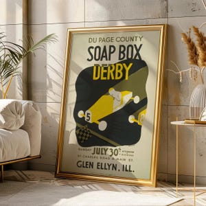 May include: A framed vintage poster for the Du Page County Soap Box Derby. The poster features a yellow race car with the number 5, set against a black and olive green background. Text includes "Sunday July 30th" and "Glen Ellyn, Ill."