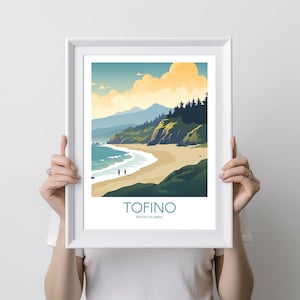 Op de afbeelding: Een ingelijste kunstdruk met een kustlandschap. Het kunstwerk toont een zandstrand, turquoise water en groene kliffen onder een blauwe lucht met wolken. Het woord "TOFINO" is in turquoise gedrukt, met daaronder "British Columbia".