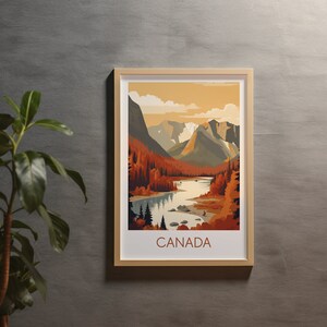 May include: Framed art print featuring a scenic landscape of Canada. The artwork depicts a river winding through a valley, surrounded by mountains and autumn-colored trees. The word "CANADA" is printed in a brown font at the bottom of the print.