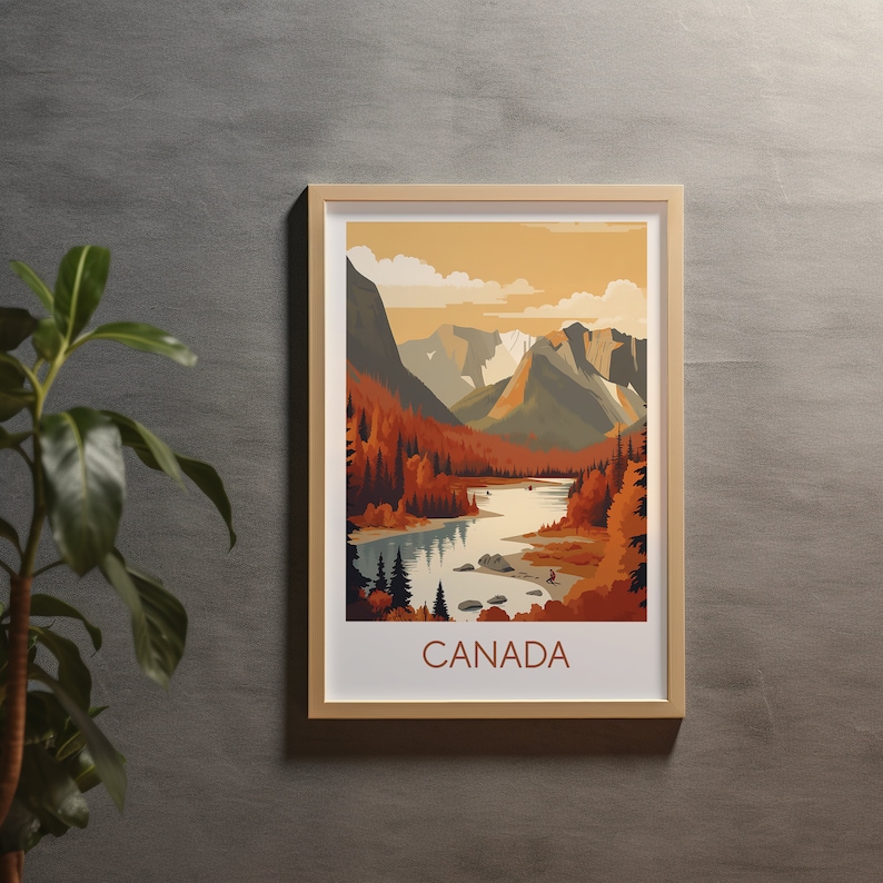 May include: Framed art print featuring a scenic landscape of Canada. The artwork depicts a river winding through a valley, surrounded by mountains and autumn-colored trees. The word "CANADA" is printed in a brown font at the bottom of the print.