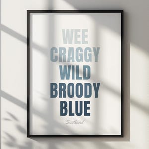 May include: A framed vertical wall art print featuring the stacked text WEE CRAGGY WILD BROODY BLUE in a gradient of blue shades, with the word Scotland written in a smaller script font at the bottom, all set against a white background.