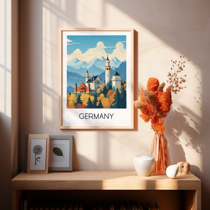 May include: A framed print of a colorful illustration of Neuschwanstein Castle in Germany. The castle is depicted in a whimsical style with a blue sky and white clouds. The text "GERMANY" is printed below the image.