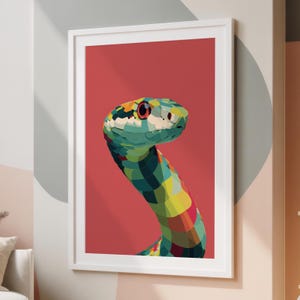 Op de afbeelding: Een ingelijste kunstdruk met een kleurrijke slangenillustratie. De kop en nek van de slang zijn afgebeeld met geometrische vormen in tinten van turquoise, geel en rood tegen een effen rode achtergrond. Het kunstwerk is ingelijst in een witte lijst.